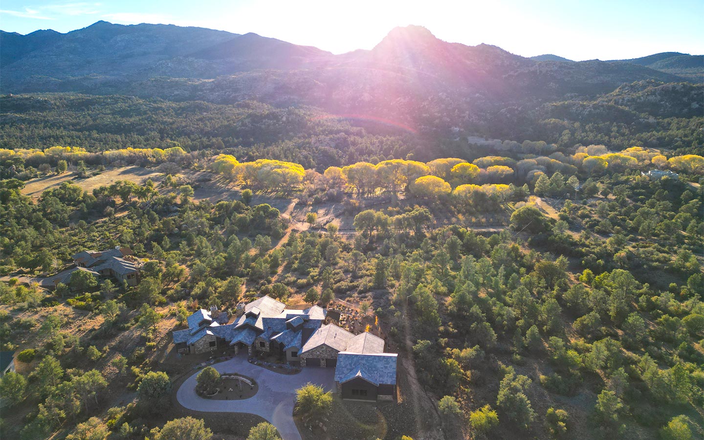 Aerial sunset view of Murphy’s Station custom home in American Ranch, Prescott, surrounded by trees and mountains
