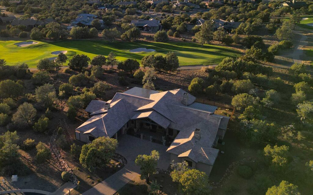 Drone view of a Prescott custom home on the golf course in Talking Rock Ranch at sunset with Granite Mountain in the background