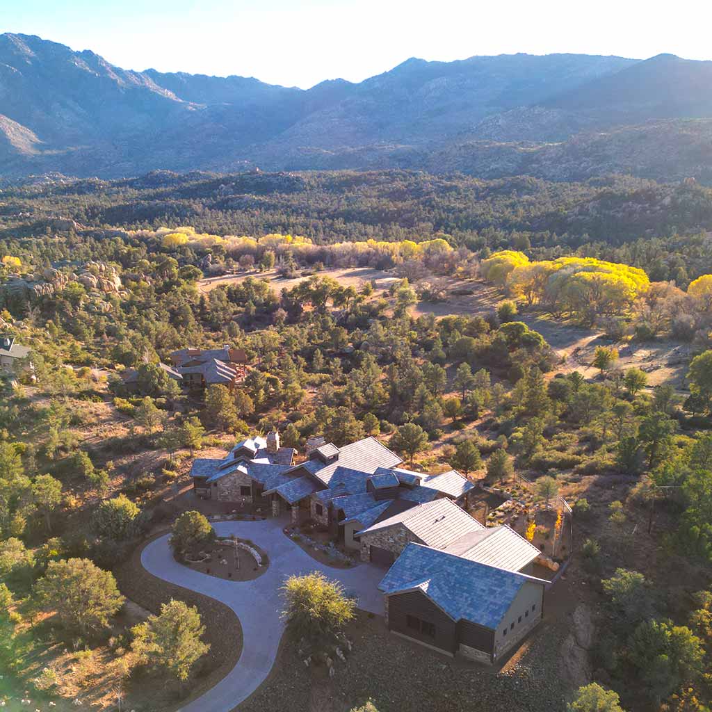 Aerial view of an expansive American Ranch Prescott custom home with Granite Mountain in the background at sunset