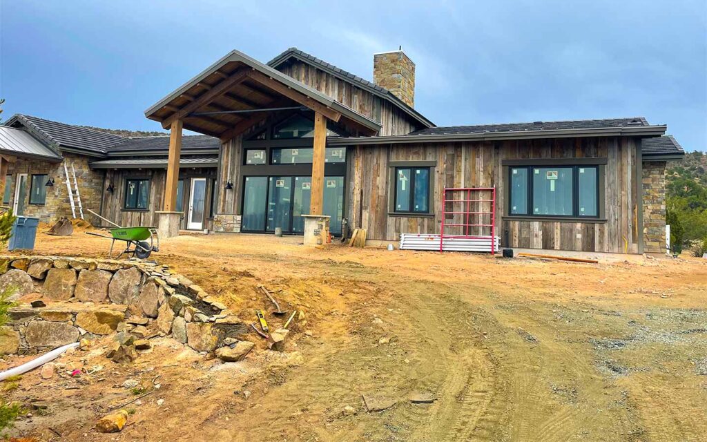 Nearly finished Prescott custom home in Talking Rock Ranch with exterior siding, stone, roof, and windows installed