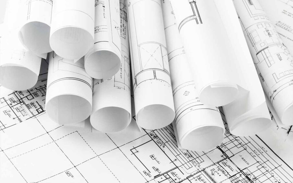 Close-up of custom home building plans laid out and rolled up for design and pre-construction planning