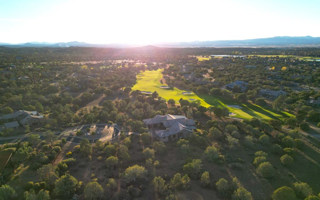 Aerial view of an HBC custom home off the fairway in Talking Rock Ranch with expansive Prescott landscape at sunset