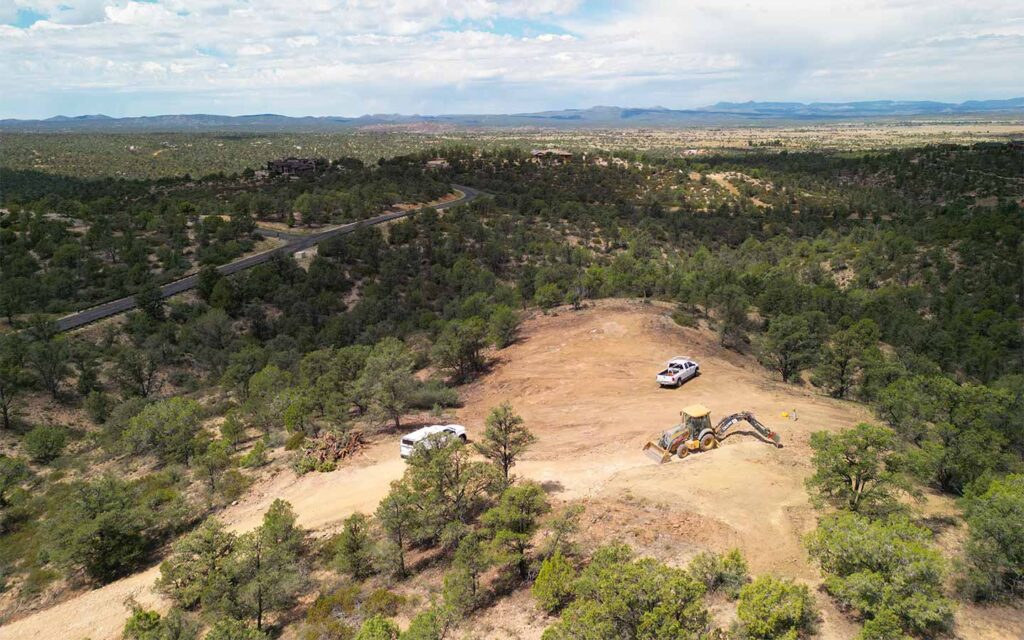 Aerial view of a Talking Rock Ranch custom home site during discovery and dirt work with work trucks and a tractor
