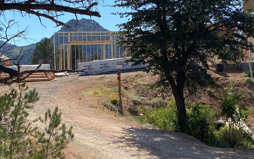 Early framing of an American Ranch custom home with native shrubs in the foreground and Granite Mountain in the background