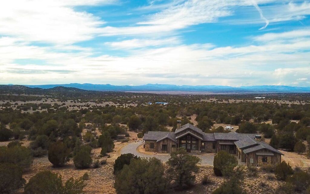 Aerial view of a Sterling Ranch custom home with open west-facing landscape views under a partly cloudy blue sky