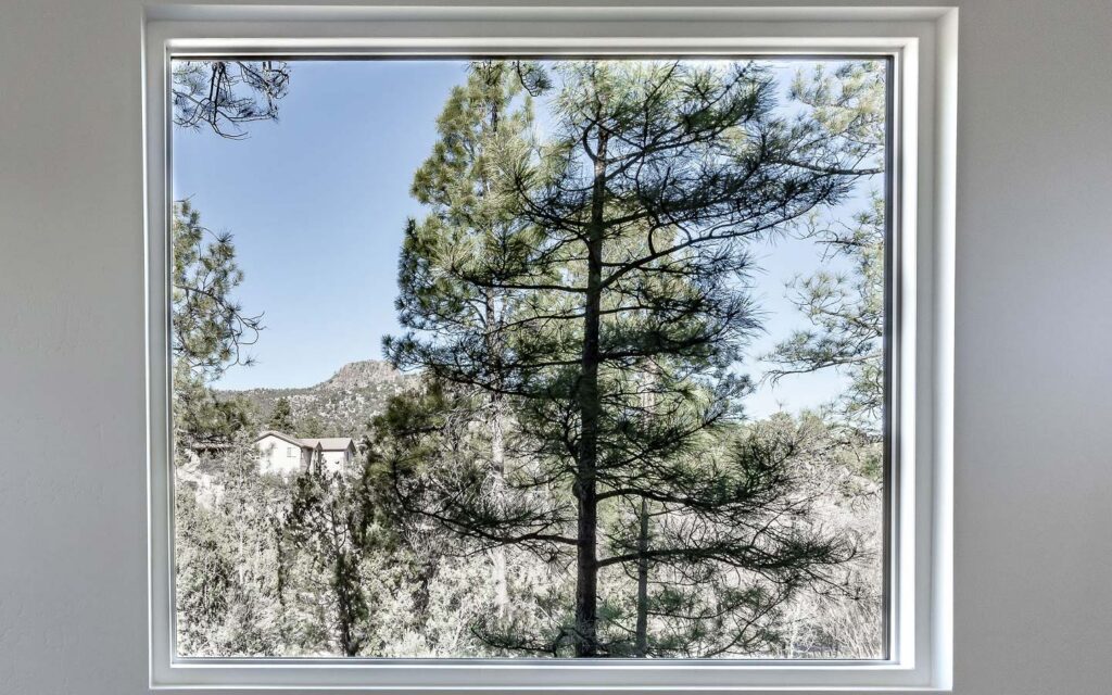 View through a picture window to pine trees and Thumb Butte near Hassayampa in Prescott, AZ