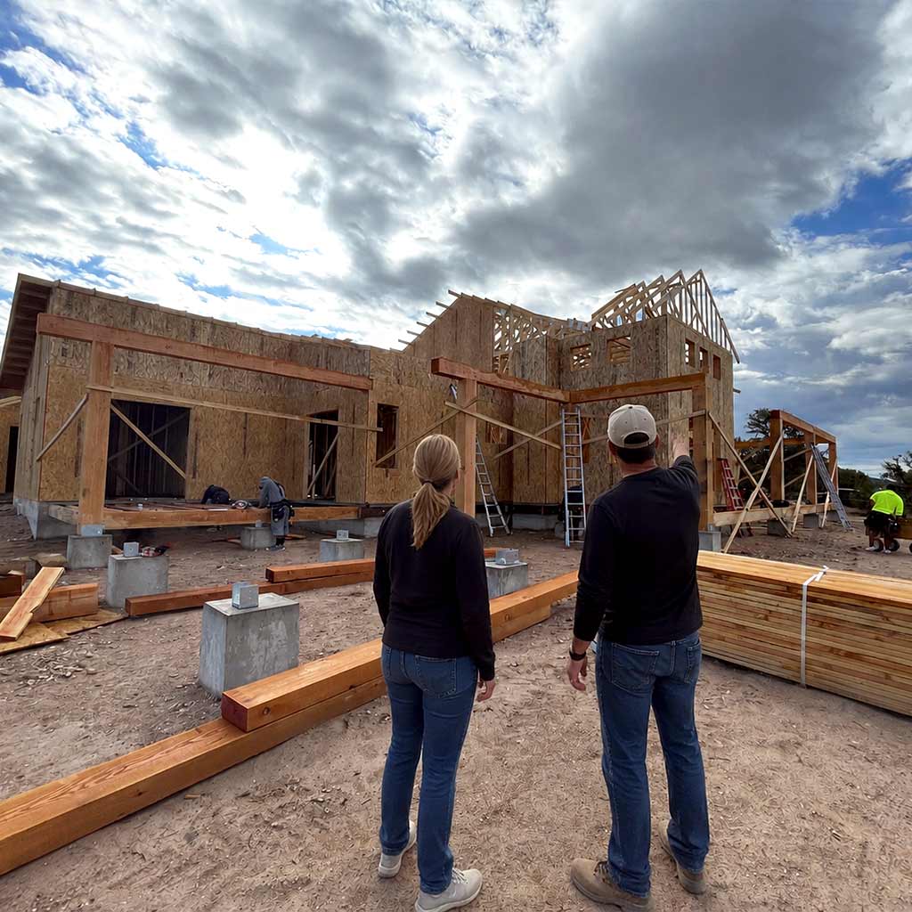 Two people reviewing an HBC custom home jobsite in Sterling Ranch before plans are finalized, with home framing and construction materials visible