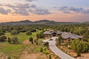 Western Trail Custom Home in Sterling Ranch - Site and Driveway Aerial | Hughes Building Company | Luxury Custom Homes | Prescott, AZ | Hughes Building Company | Luxury Custom Homes | Prescott, AZ Western Trail custom home in Sterling Ranch viewed from above with its long paver driveway, surrounding acreage, and Prescott landscape