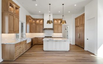 Wide view of Sterling Ranch custom home kitchen with island, farmhouse sink, and full-height cabinetry