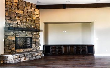 Stone fireplace with custom dark wood entertainment center in Kokopelli great room at Talking Rock Ranch custom home in Prescott, AZ