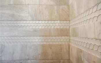 Light stone-look shower tile with flowing wave accent bands in Kokopelli, a Talking Rock Ranch custom home